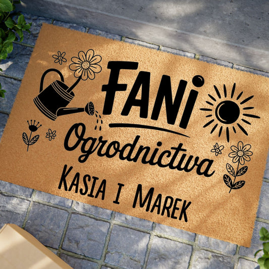 Wycieraczka z napisem „Fani Ogrodnictwa” z personalizowanymi imionami i grafiką kwiatów, słońca i konewki.