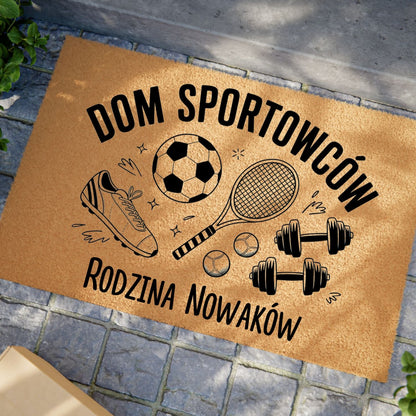 Wycieraczka z napisem „Dom Sportowców” i personalizowanym nazwiskiem, ozdobiona motywami sportowymi.