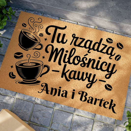 Wycieraczka z napisem „Tu rządzą miłośnicy kawy” i filiżankami kawy, z personalizacją imion.